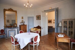 Una habitación con una mesa de comedor, sillas, chimenea, sofá, estantería y un espejo grande.