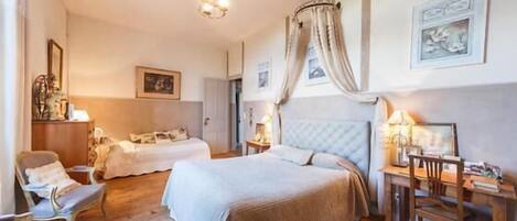 A bedroom with two beds, a desk, and a chair.