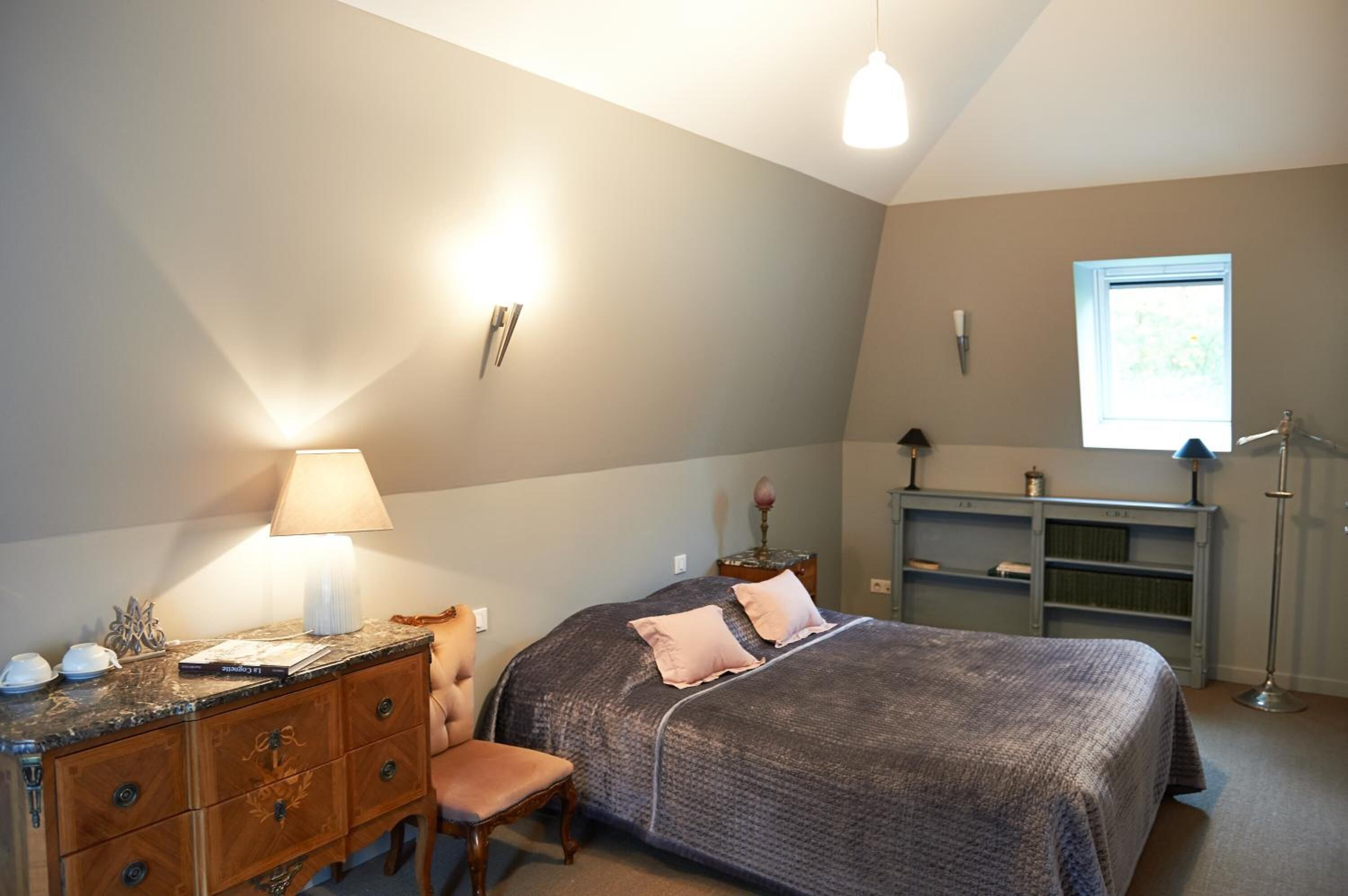 A bedroom with a bed, a dresser, a chair, a desk, and a window.