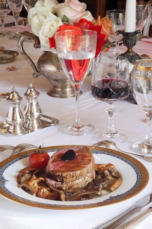 Enjoy a formal dining experience with a beautifully set table, complete with a delicious meal, fresh flowers, and fine wine.
