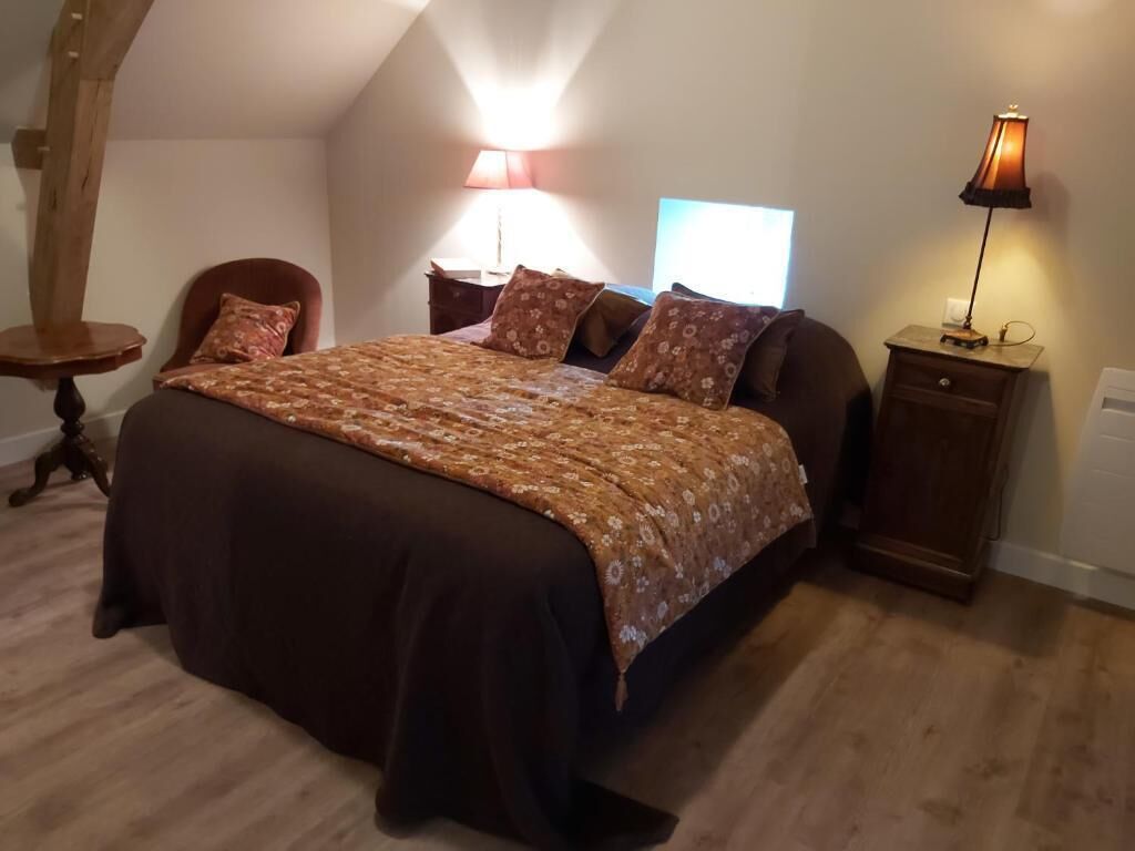 A bedroom with a large bed, a nightstand, a lamp, and a chair.