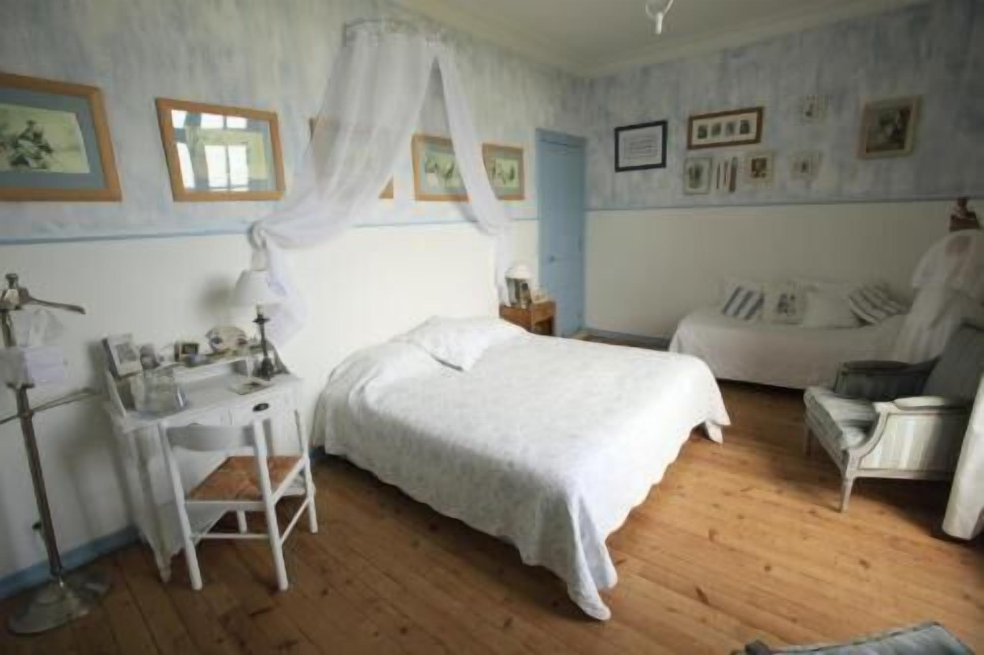 Un dormitorio con cama, escritorio, silla y mesita de noche.