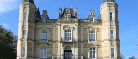 A large, historic building with a symmetrical facade, multiple windows, and two prominent towers.