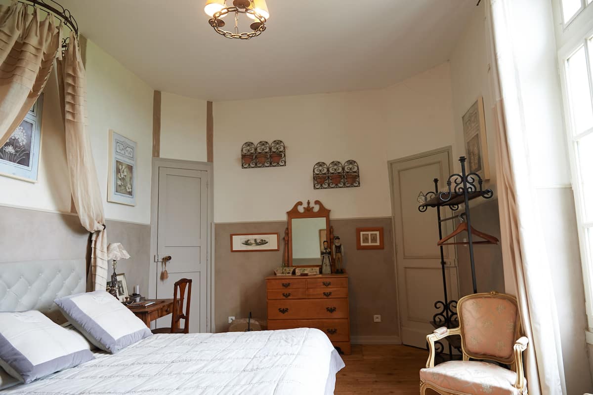A bedroom with a bed, dresser, chair, and a mirror.