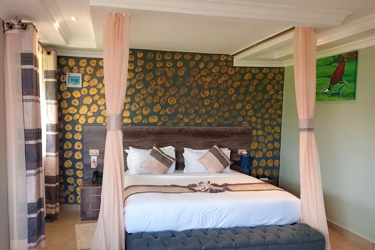Un dormitorio con cama con dosel, cabecera de madera y pared con estampado.