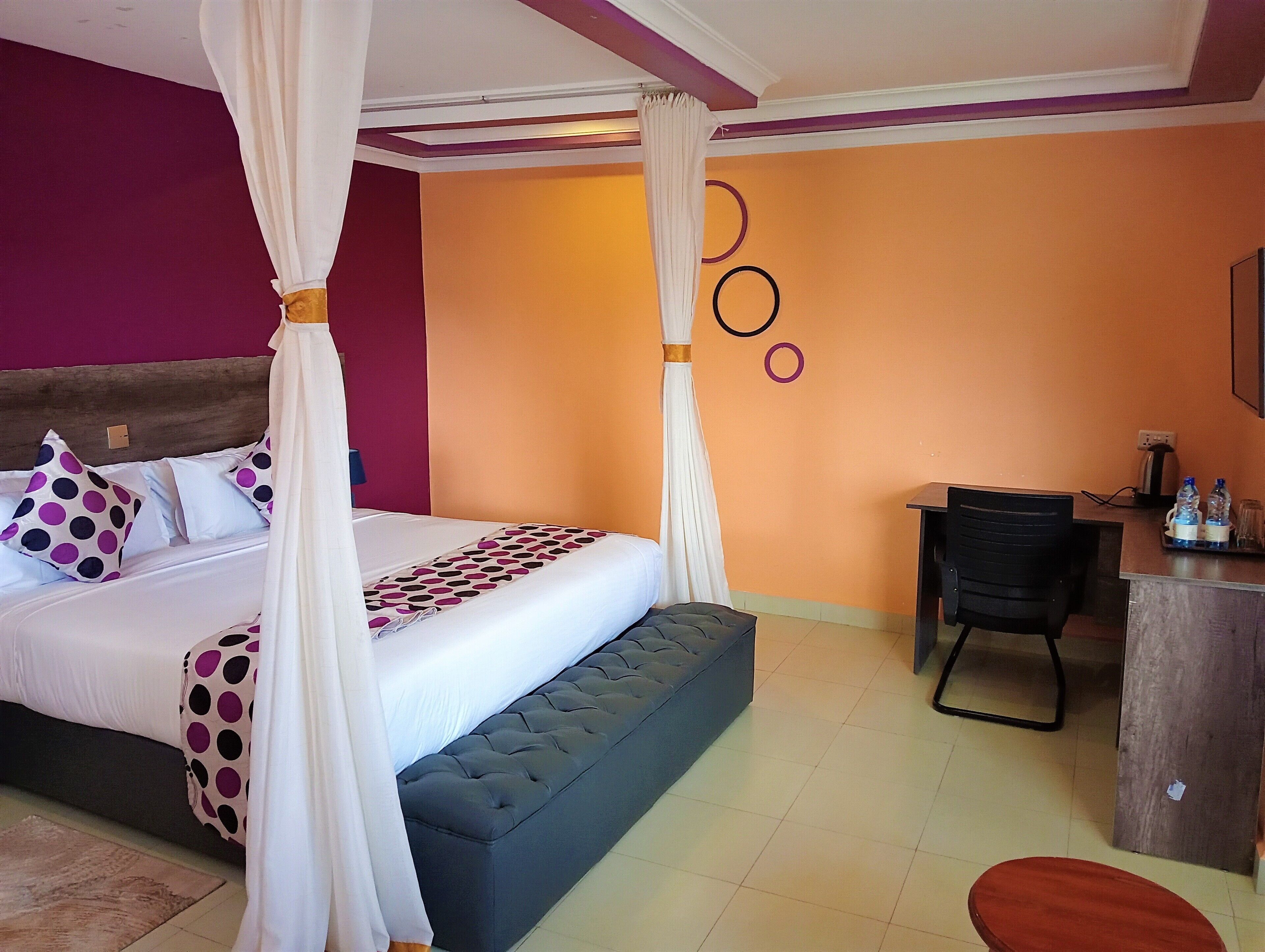 A bedroom with a four-poster bed, a desk, and a chair.