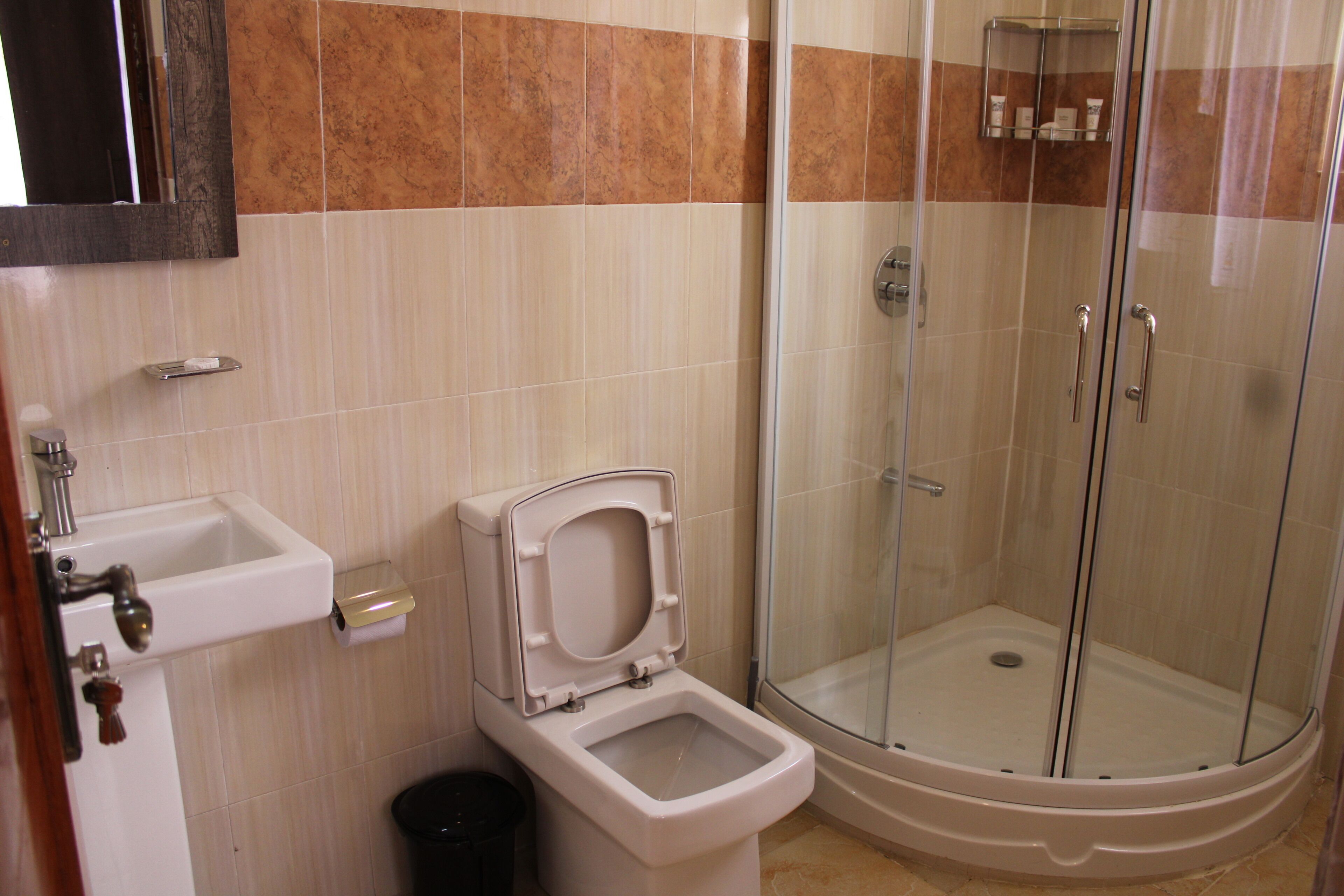 Un baño con inodoro, lavamanos y ducha con mampara de vidrio.