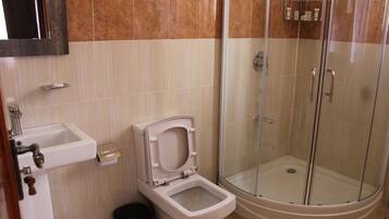 Un baño con inodoro, lavamanos y ducha con mampara de vidrio.
