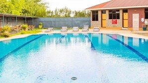 Piscina com espreguiçadeiras e um edifício com telhado em azulejos.