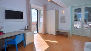 A modern room with a flat-screen TV, a blue chair, a white bench, and a balcony with a view. - Casa Mao (Amalfi)