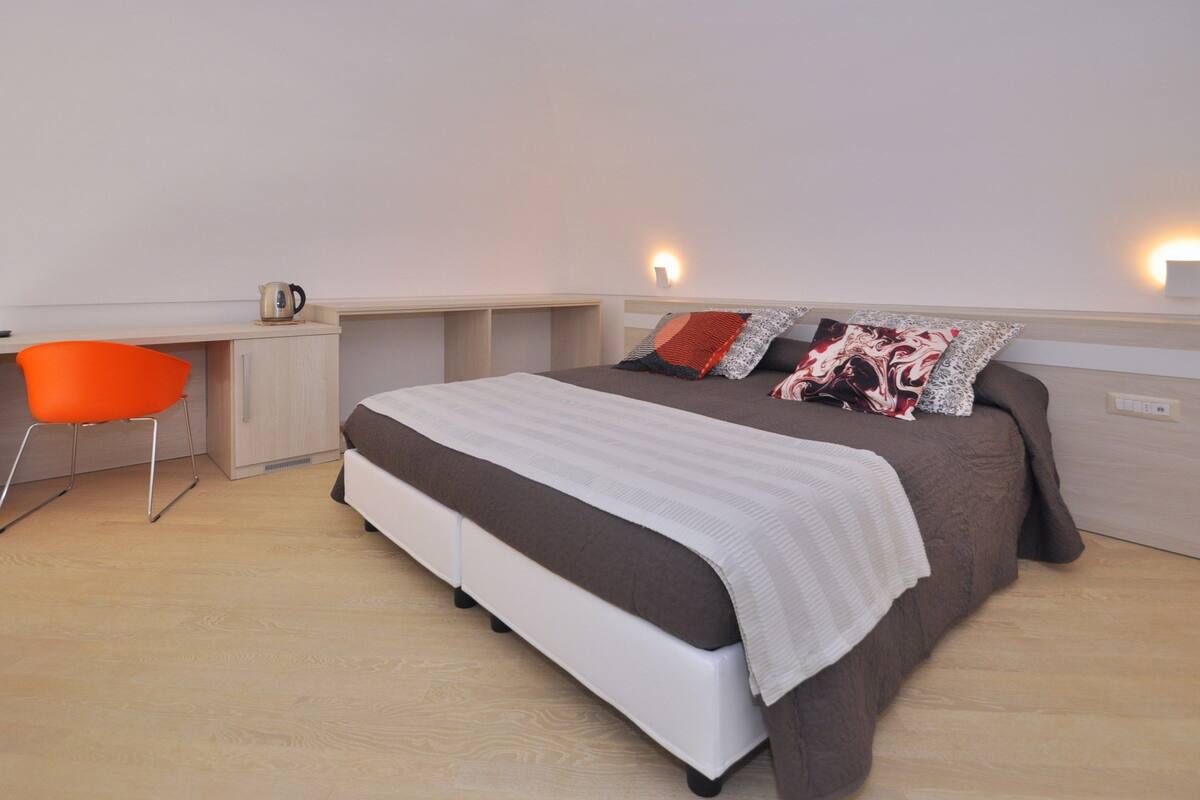 Un dormitorio moderno con una cama, un escritorio y una silla.