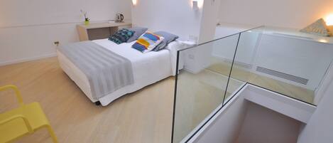 A modern bedroom with a bed, bedside table, lamp, and a glass railing.