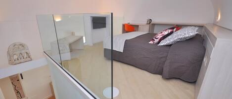 A bedroom with a bed, a desk, and a chair.