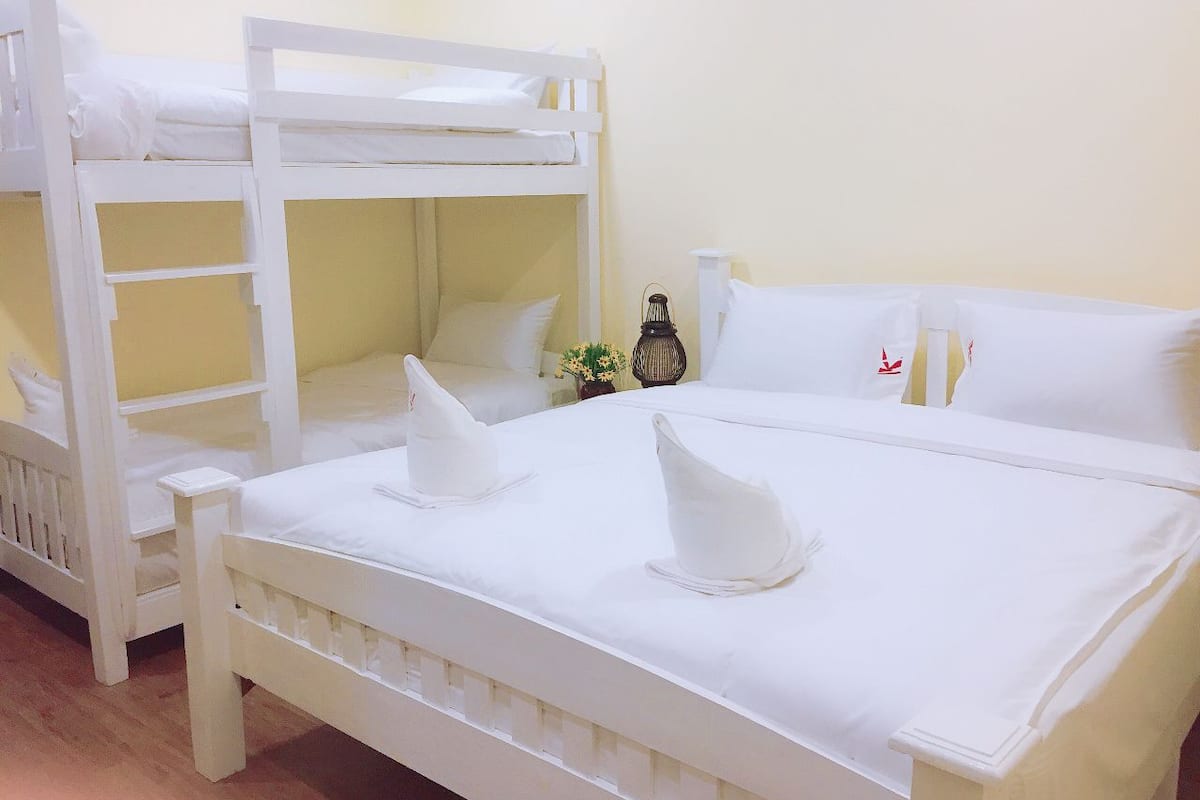 A room with two white bunk beds and a single bed with white bedding.