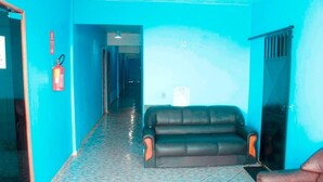 A room with a blue wall, a black leather sofa, and a tiled floor. - Grand Center Hotel (Santarém)