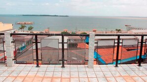 A view from a balcony overlooking a beach with a distant island and a ship in the water. - Grand Center Hotel (Santarém)
