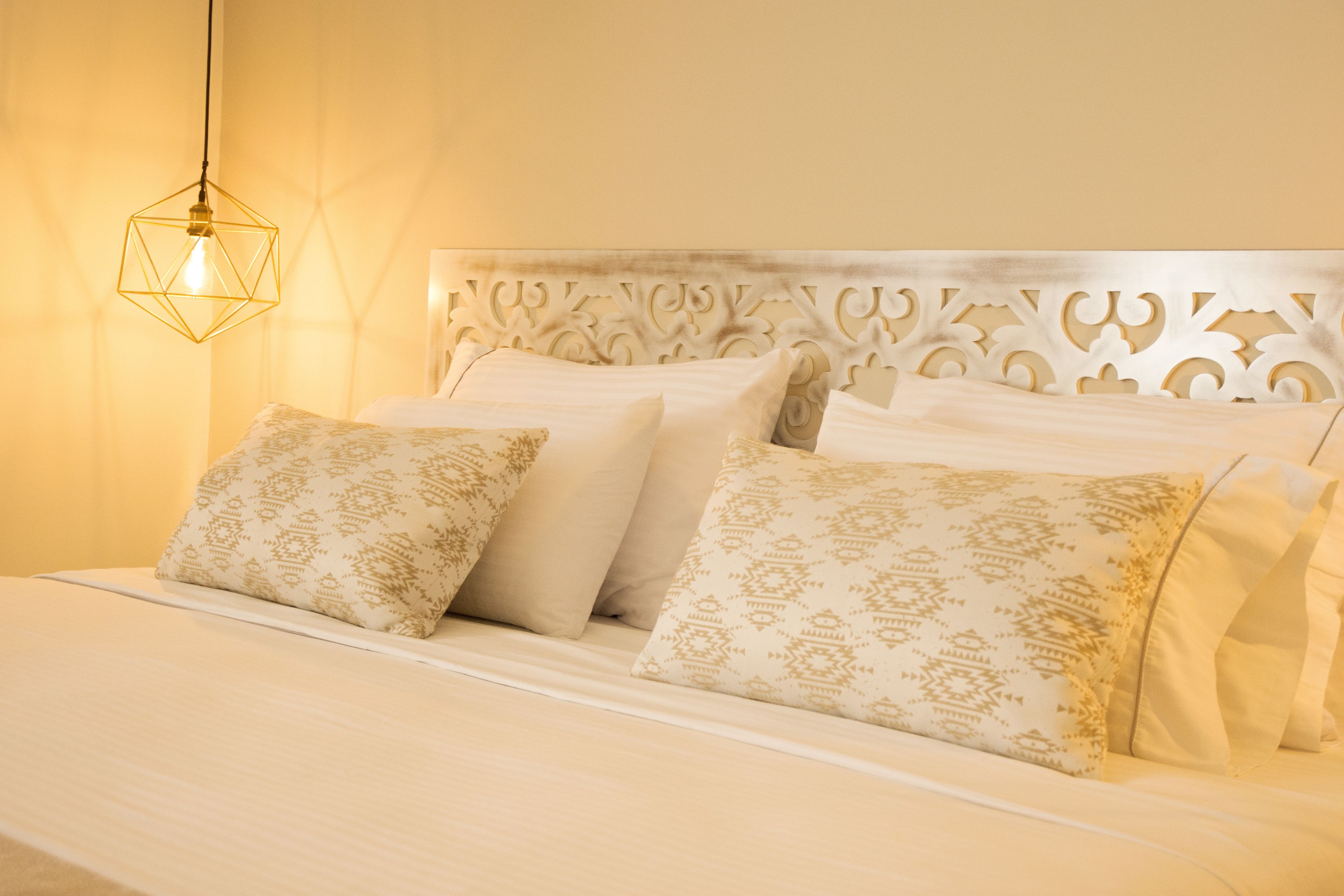 A bed with a white headboard and patterned pillows.