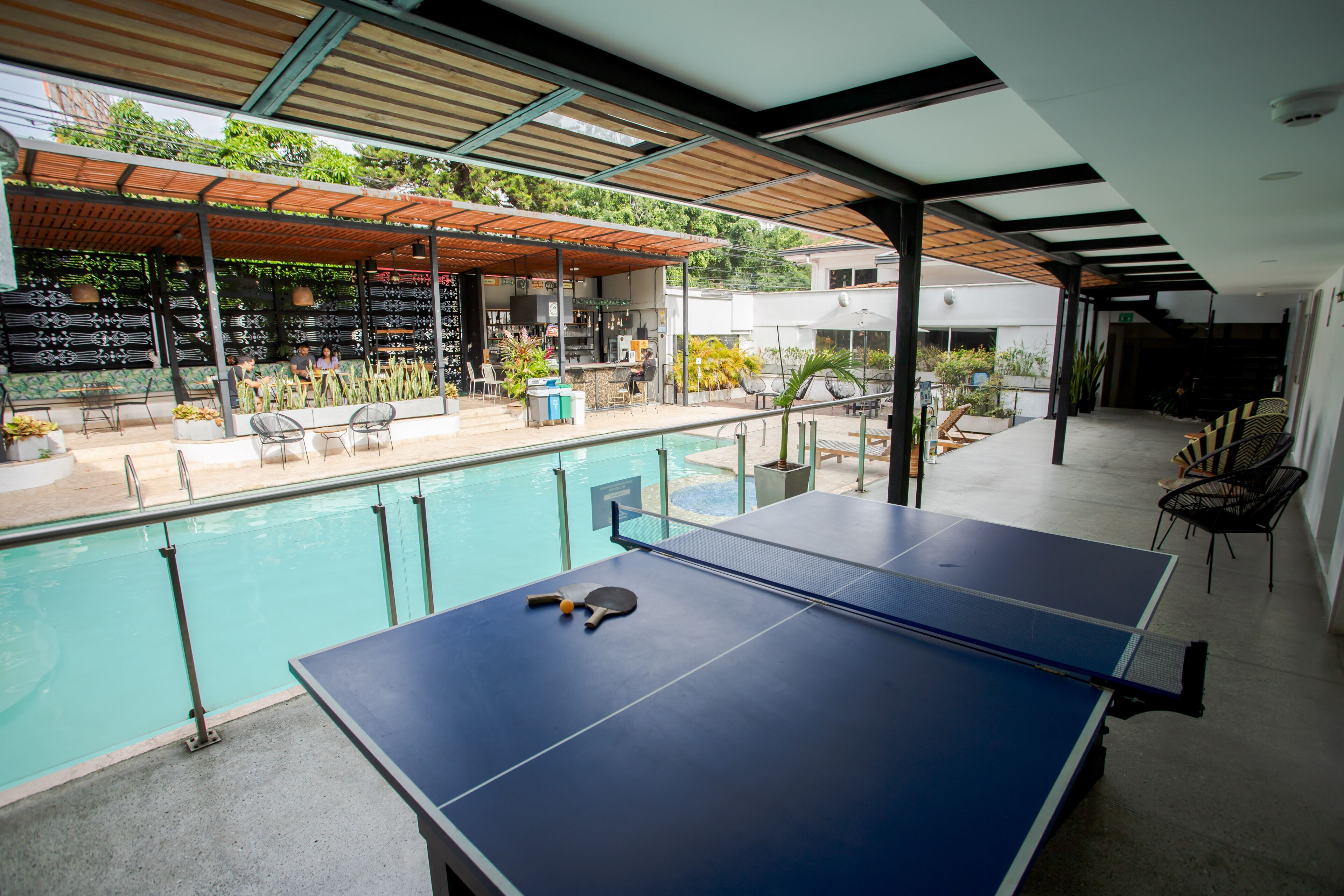 A poolside area with a ping pong table, chairs, and a bar.