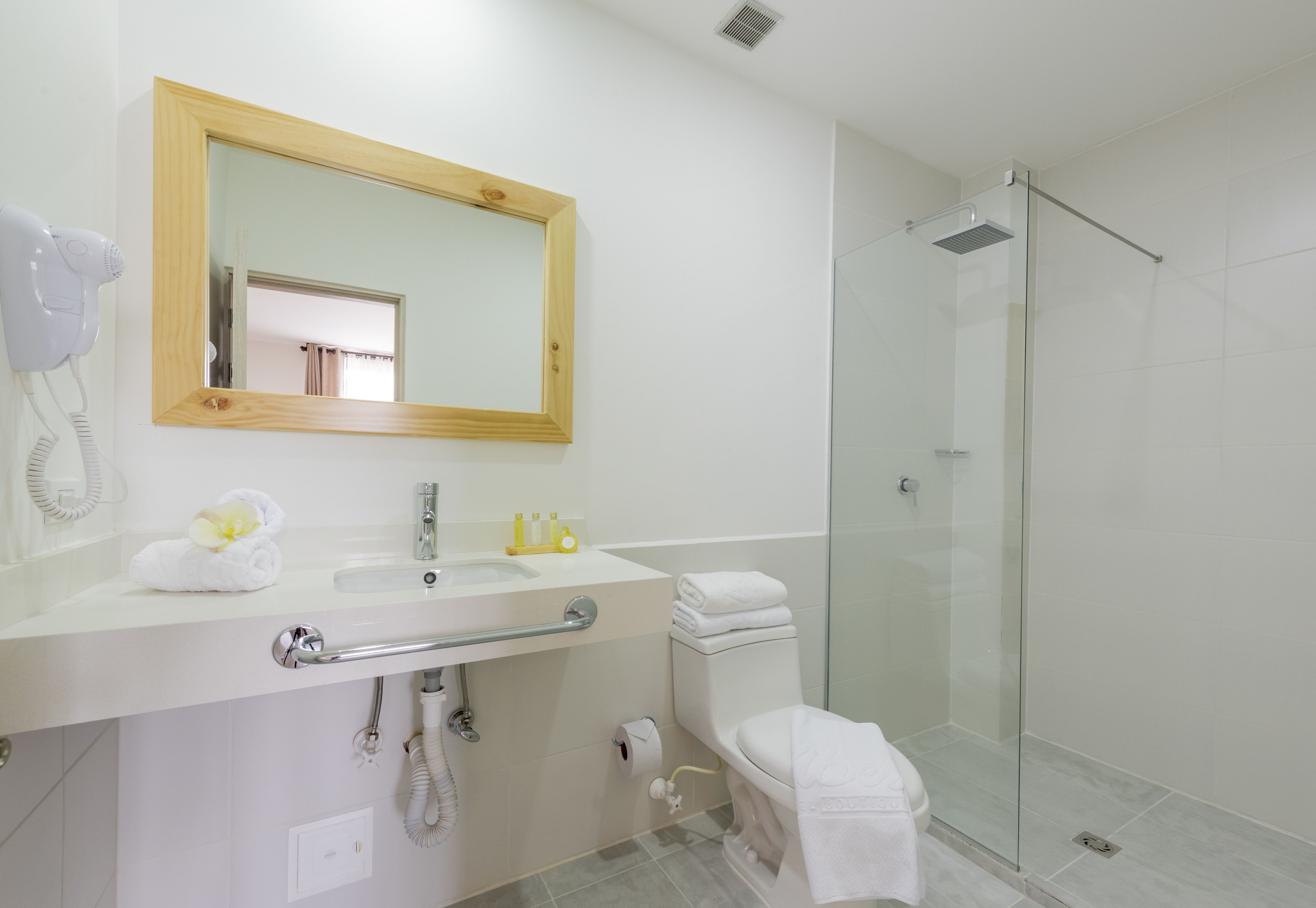 A bathroom with a sink, mirror, towel, toilet, and glass shower enclosure.