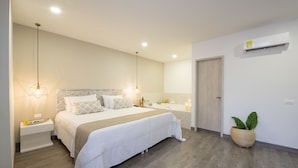 A modern bedroom with a large bed, bedside tables, a nightstand, a potted plant, and an air conditioning unit. - Medellín Vibes (Medellín)