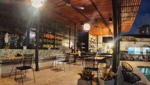 An outdoor seating area with tables and chairs, a pool, and potted plants. - Medellín Vibes (Medellín)