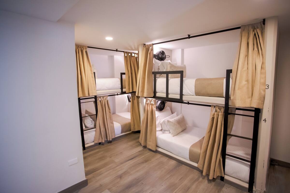 A bunk bed room with curtains, a ceiling fan, and a wooden floor.