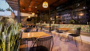 An indoor dining area with wooden tables and black metal chairs, surrounded by large windows with decorative glass panels. - Medellín Vibes (Medellín)