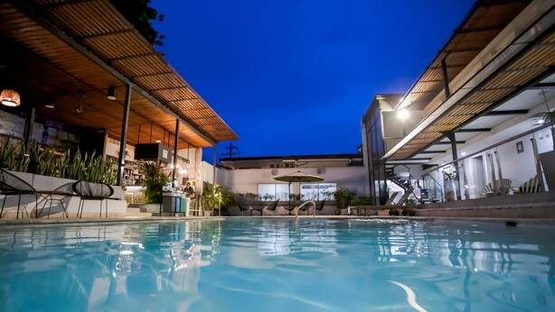 A pool area with a covered seating area, a bar, and a staircase leading to an upper level. - Medellín Vibes (Medellín)