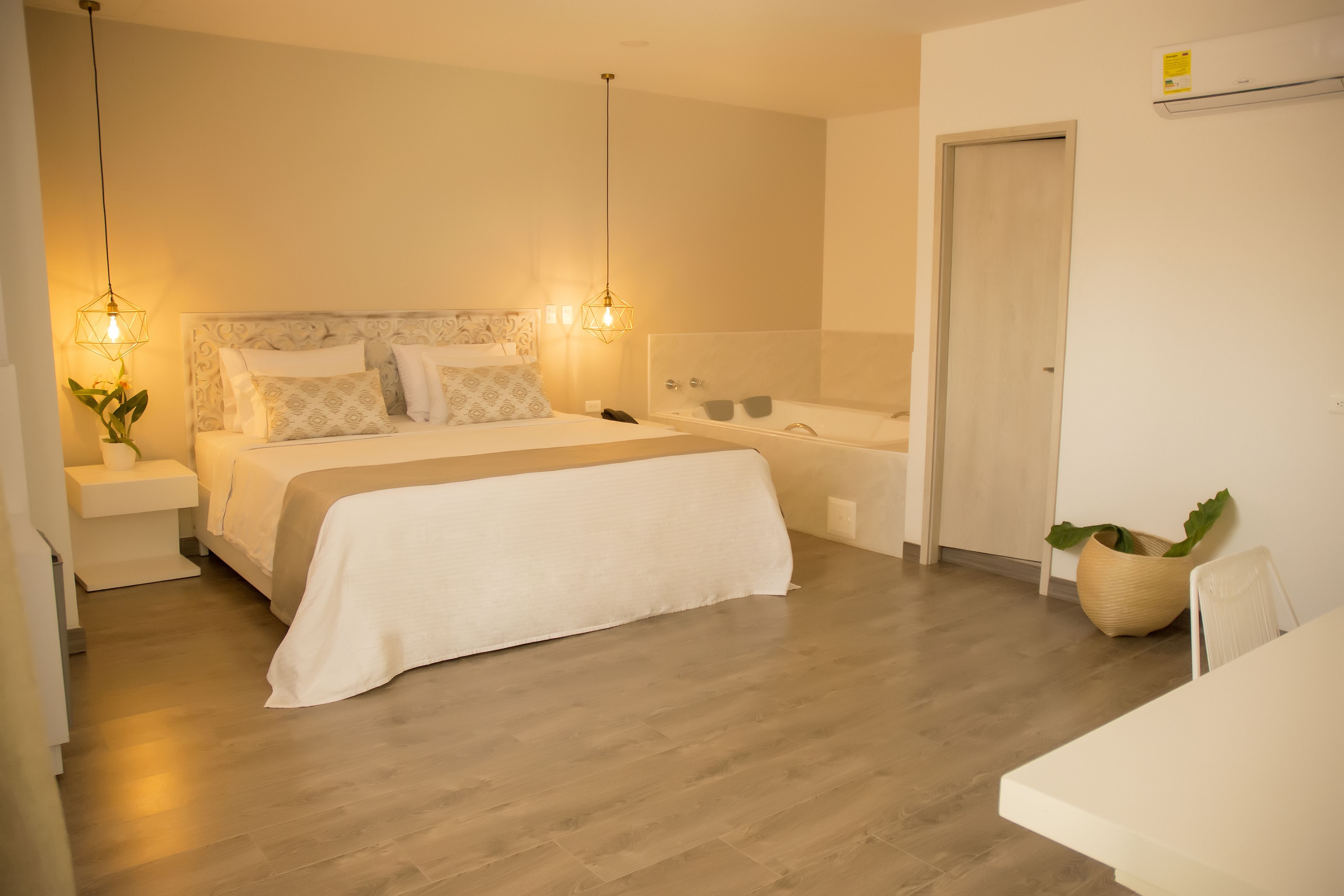 Un dormitorio moderno con cama, mesitas de noche, lámpara de pared y una planta pequeña.