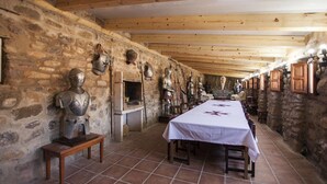 Ein langer Esstisch mit weißer Tischdecke, begrenzt von Steinwänden und Holzbalken.