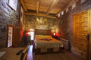Een gezellige kamer met een stenen muur, houten plafond en een grote houten deur.