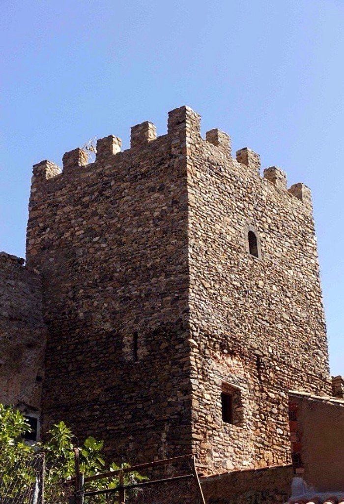 A stone tower with crenellations, a small window, and a metal railing in the foreground.