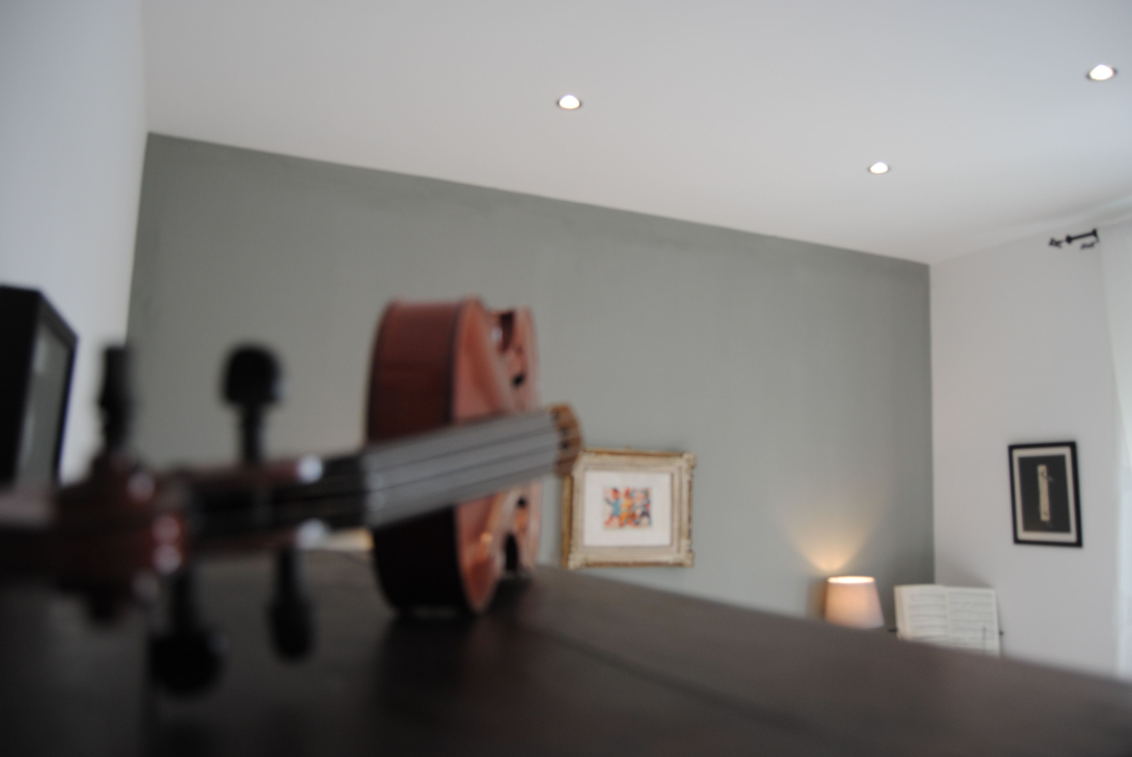 Une pièce avec une table en bois foncé, un violon et un tableau encadré accroché au mur.