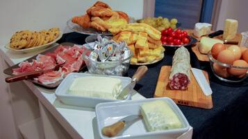 Un tavolo per buffet con diverse pietanze, tra cui carni, formaggi e dolci.