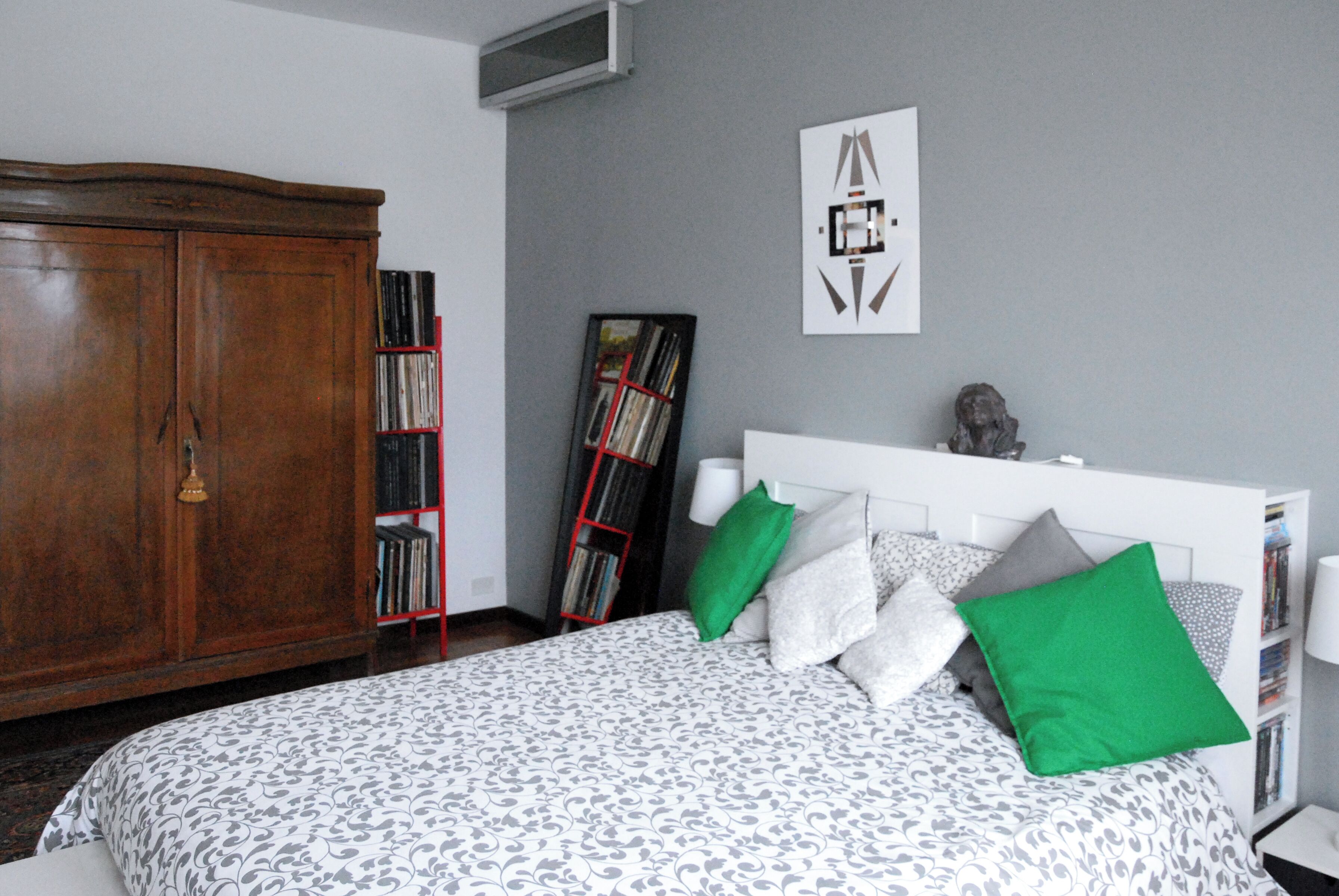 Un dormitorio con una cama, un armario de madera, una estantería y un cuadro en la pared.
