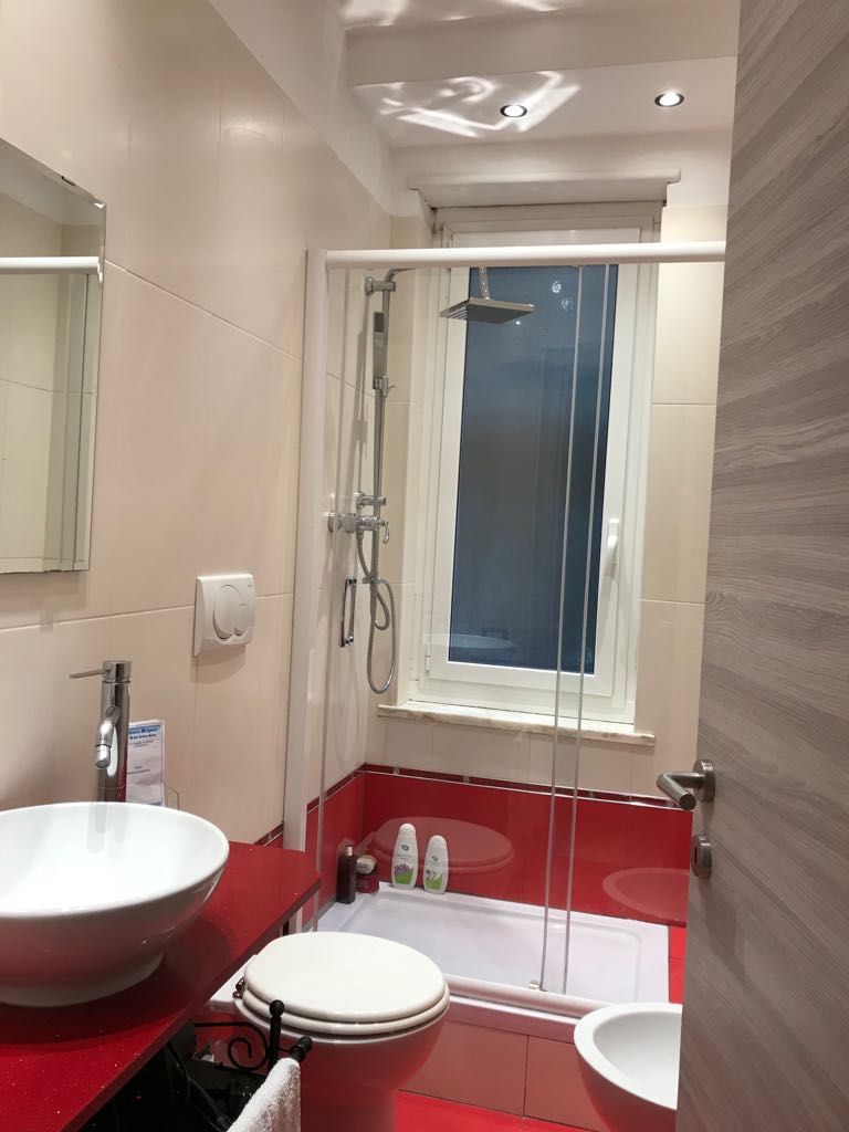 A modern bathroom with a glass-enclosed shower, a white sink, a toilet, and a bathtub.