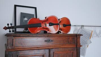 A violin on a wooden cabinet with a framed picture and sheet music in the background.