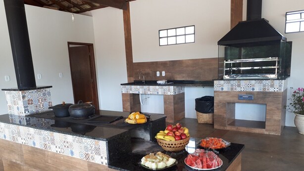 A kitchen with a central island, a built-in oven, and a variety of fruits and vegetables on the counter.