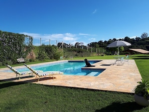 A swimming pool with lounge chairs and a gazebo. - Pousada Leolud (Socorro)
