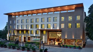 A modern hotel with a flat roof, multiple windows, and a well-lit entrance. - Radisson Gwalior (Gwalior)