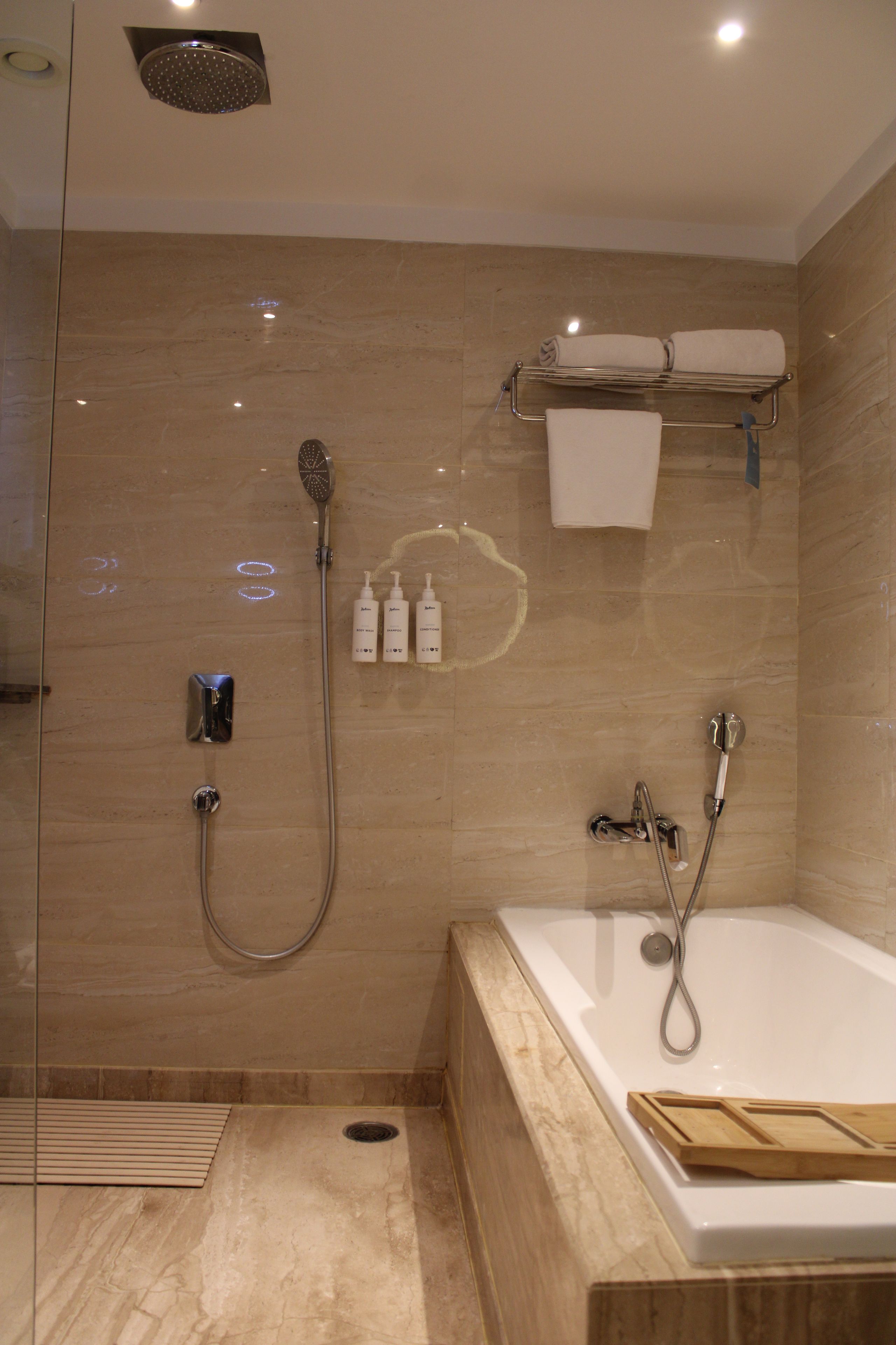 Un baño moderno con ducha envuelta en vidrio, bañera separada y tocador con perchero.