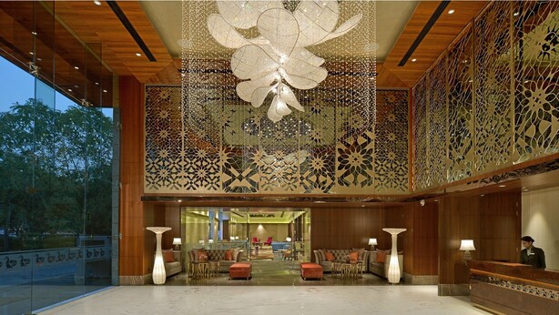 A spacious lobby with a marble floor, a reception desk, and a large decorative ceiling piece. - Radisson Gwalior (Gwalior)