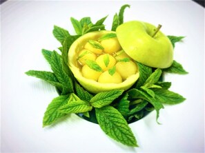 A bowl of sliced apples surrounded by mint leaves. - Botaniq Hotel Boutique (Mojacar)