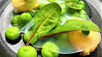A dish with greens and a yellow item on a black plate.