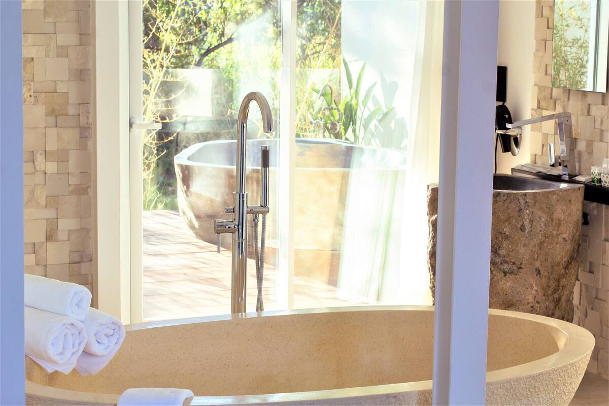 A modern bathroom with a large bathtub, a shower, and a sink.