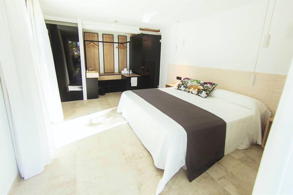 A hotel room with a bed, a bedside table, a mirror, and a wardrobe.