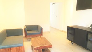 A modern living room with a sofa, a chair, a coffee table, and a TV on a cabinet. - Botaniq Hotel Boutique (Mojacar)