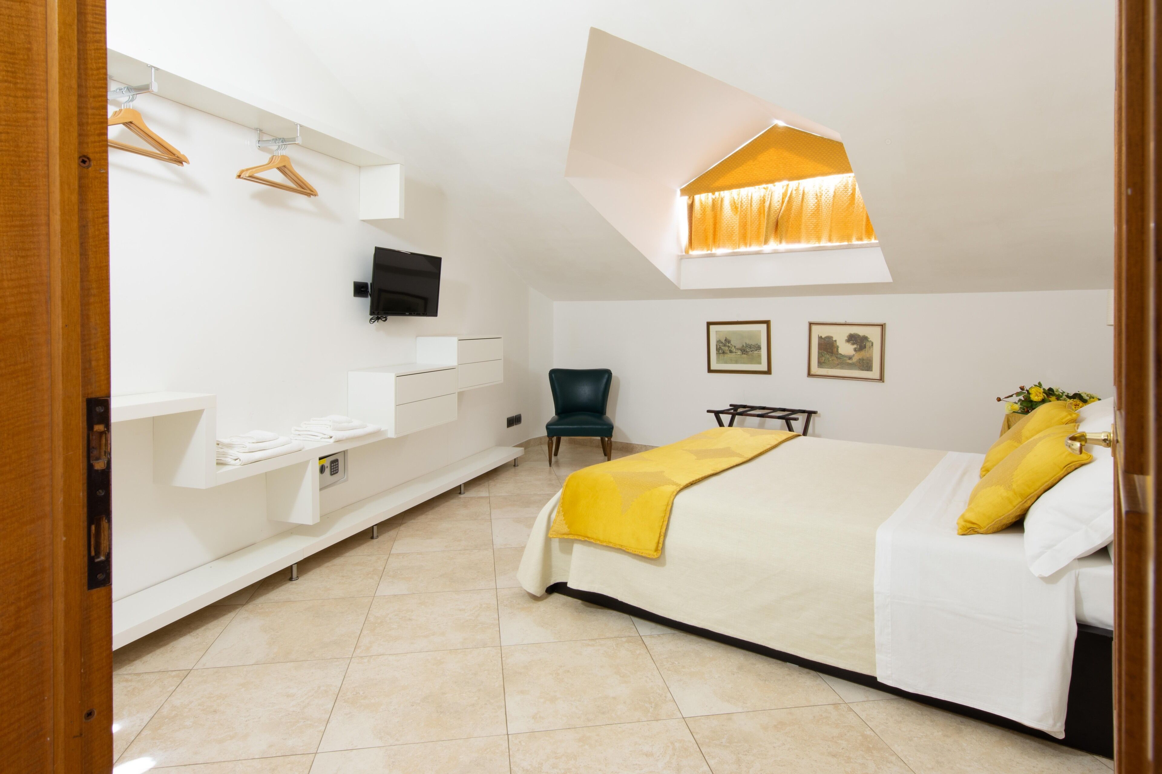 A hotel room with a bed, a chair, a desk, a TV, and a window with curtains.