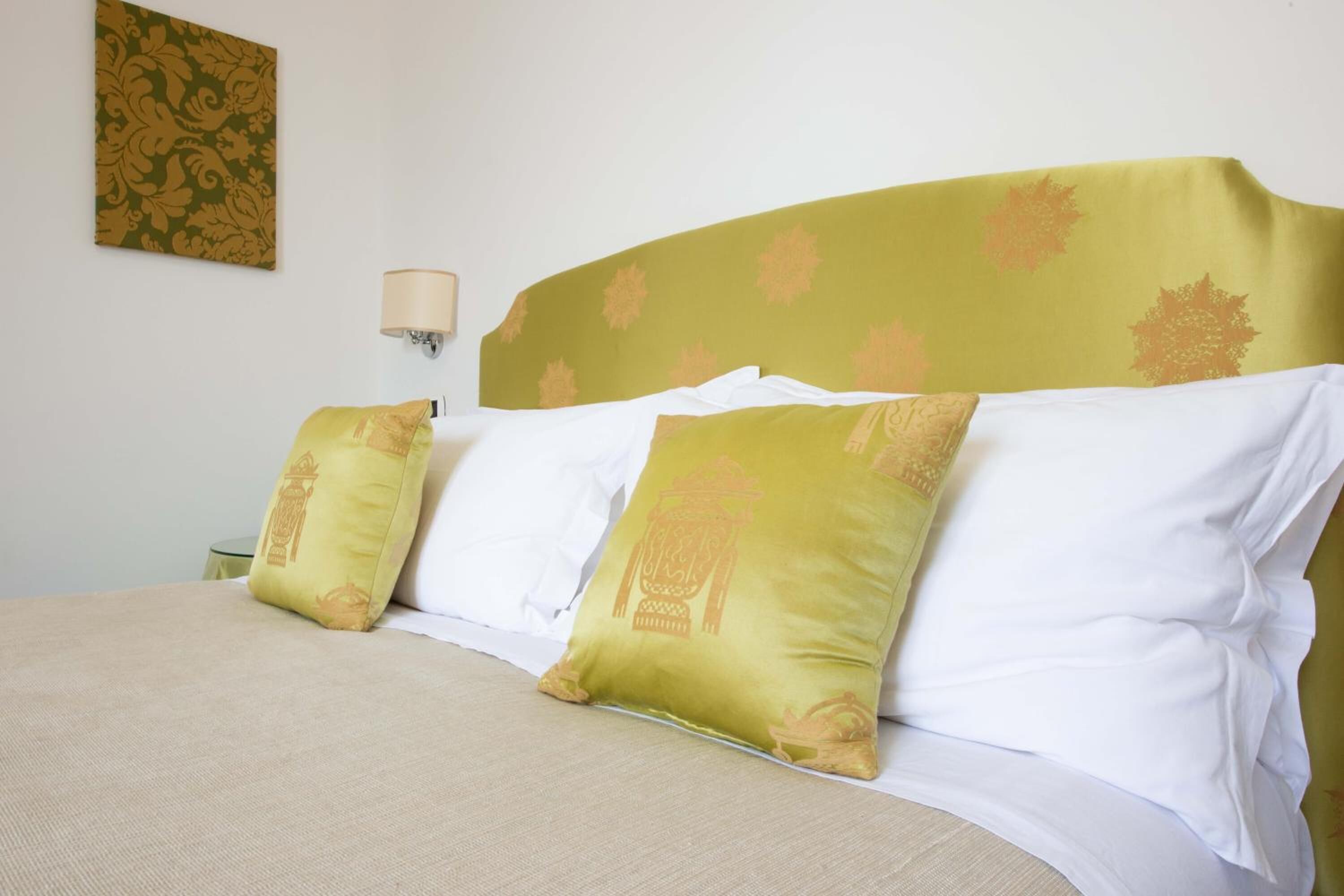 A bed with a green headboard, white bedding, and decorative pillows.