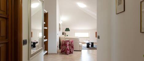 A hallway leading to a living area with a sofa, a table, and a lamp.